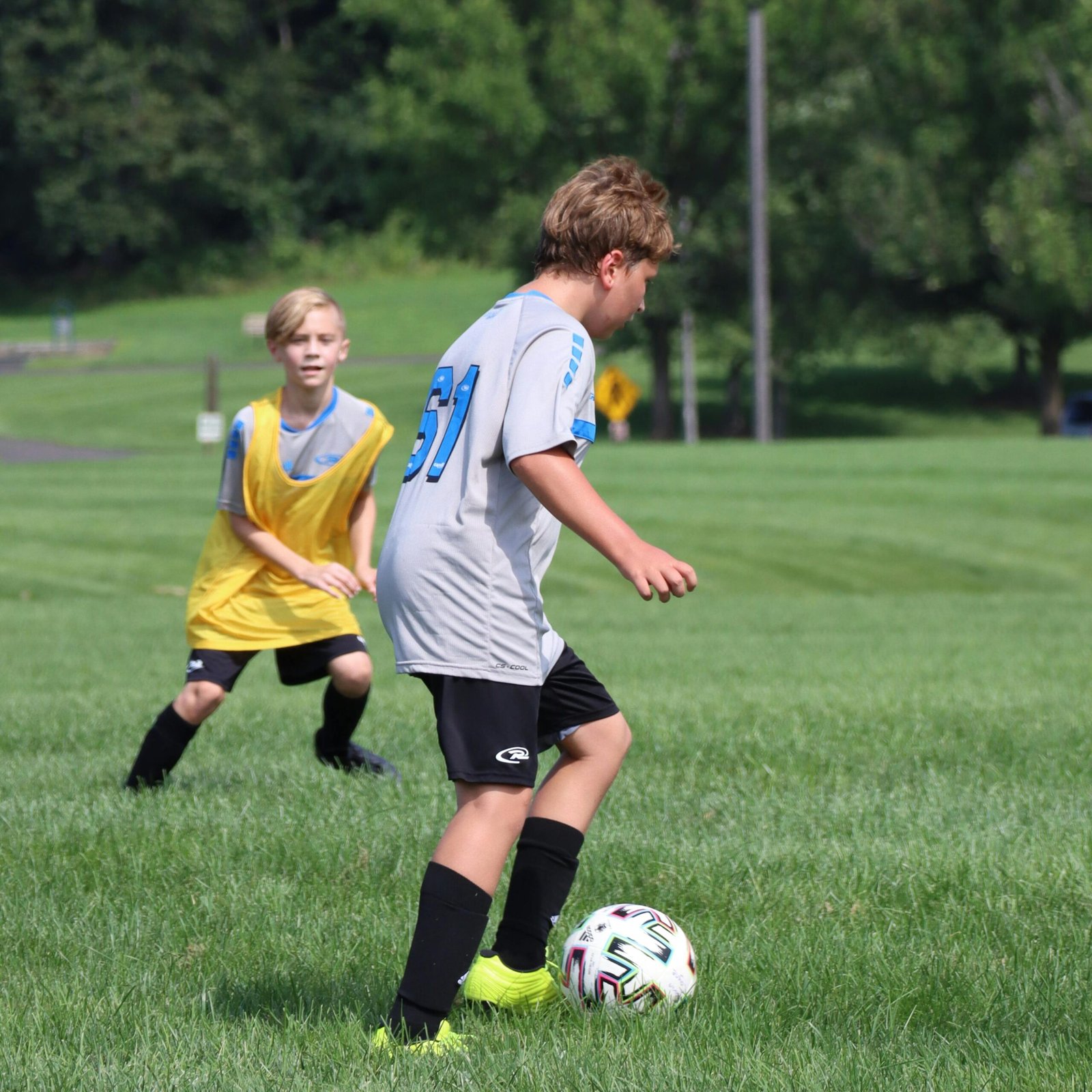 Dribbling the soccer ball in front of the opposing player.